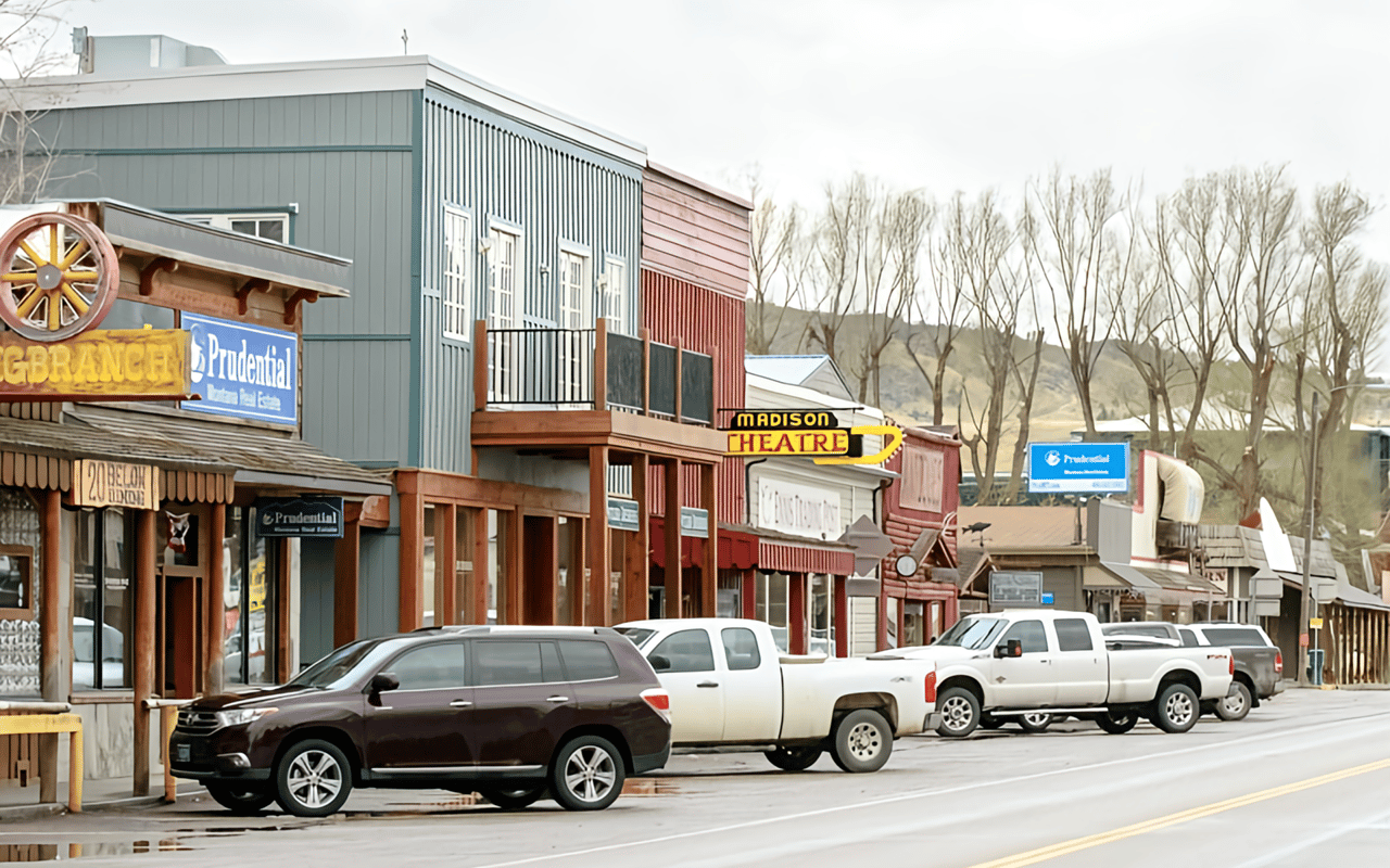 A quaint street scene in what appears to be a small town or village, lined with various rustic-style buildings that house businesses. 