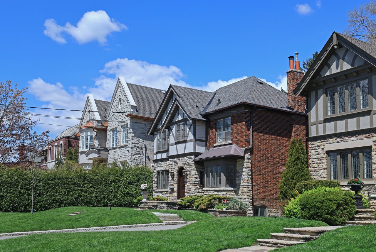 Detached homes with stone and brick facades and landscaped front lawns.