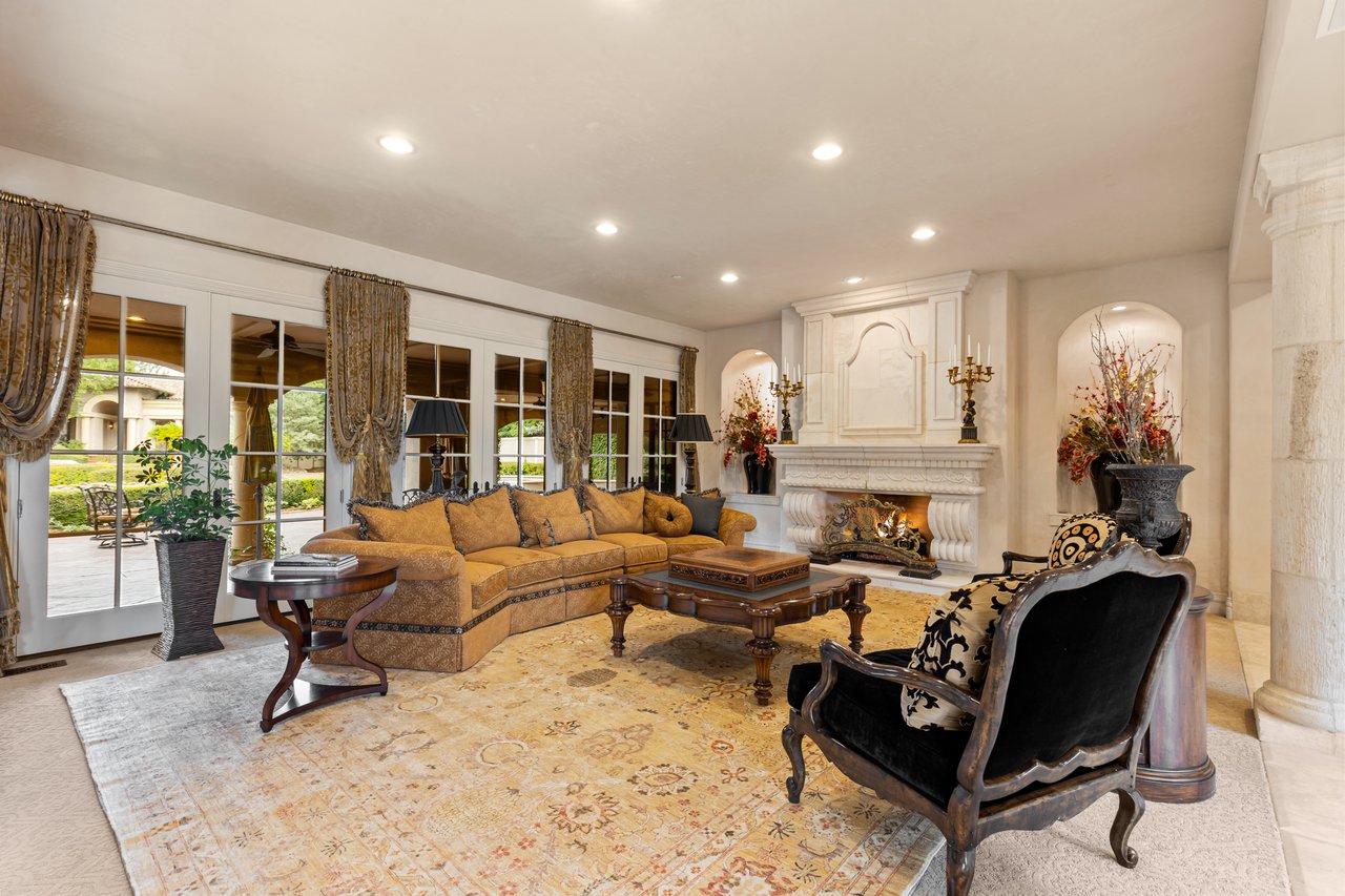 Living room with an ochre sectional, ornate white fireplace, and French doors opening onto a patio.