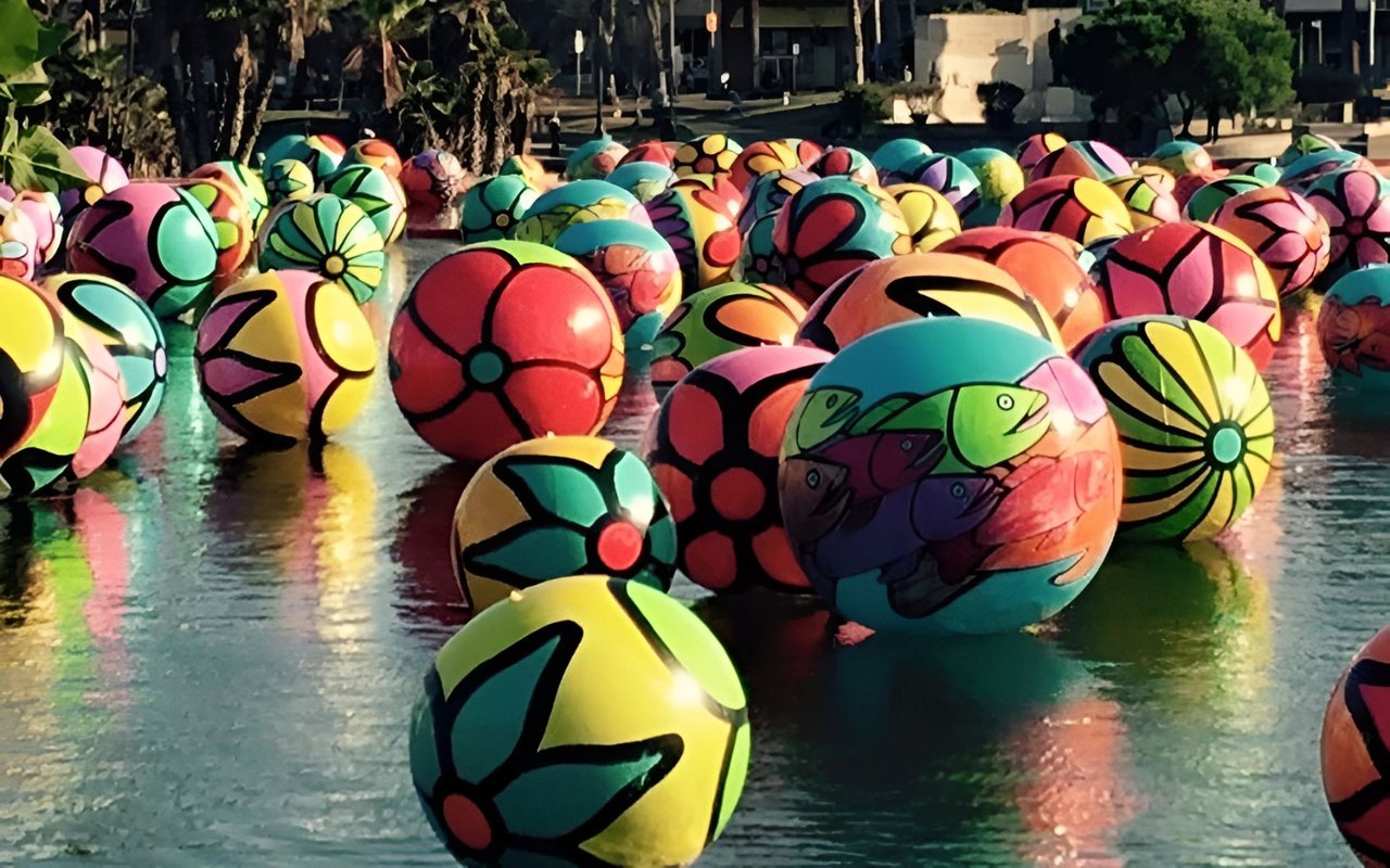 Colorful patterned spheres float in an outdoor pool.