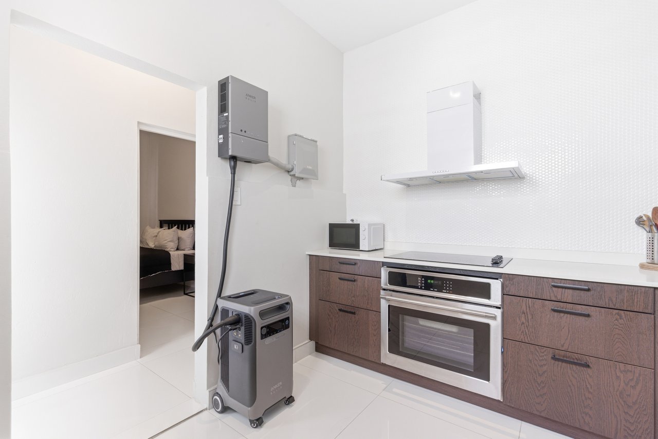 Modern kitchen with dark wood cabinets, stainless-steel oven, and a portable power unit.