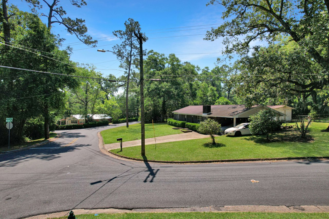 A street-level view of Marby Park showing an intersection in a residential area. The streets are lined with trees, and houses are visible in the background.