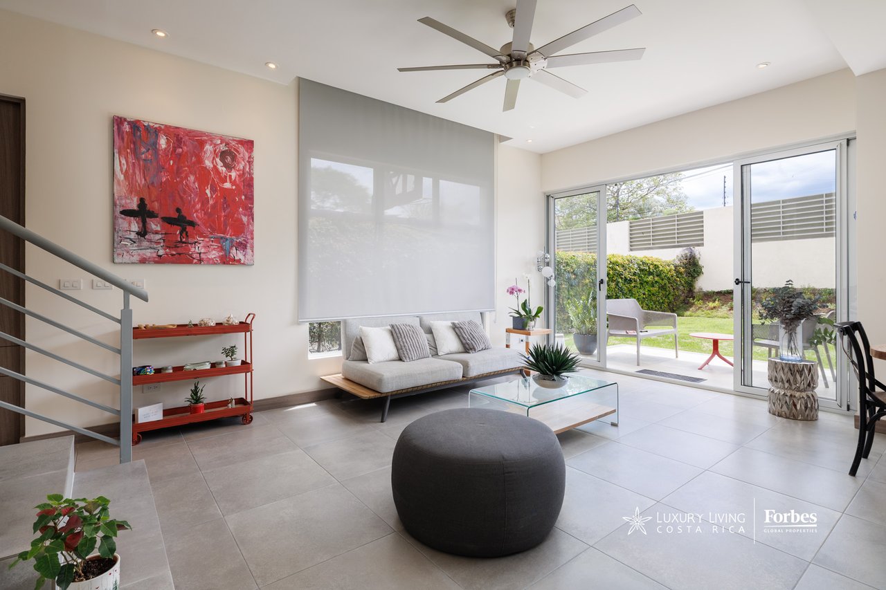 Living room with a gray sofa and sliding glass doors opening onto a private garden patio.