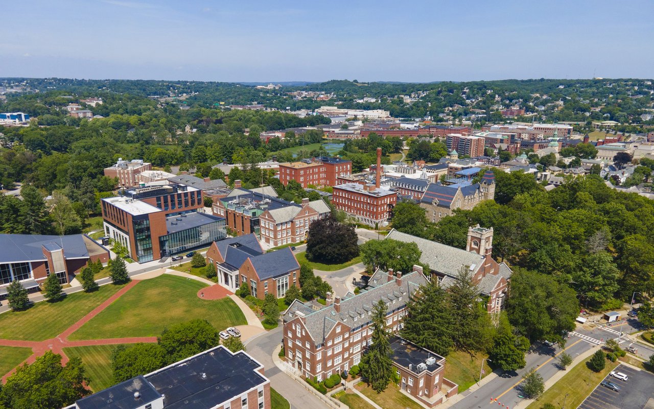 Aerial view of a Massachusetts town with leafy neighborhoods, brick buildings, and an athletic field.