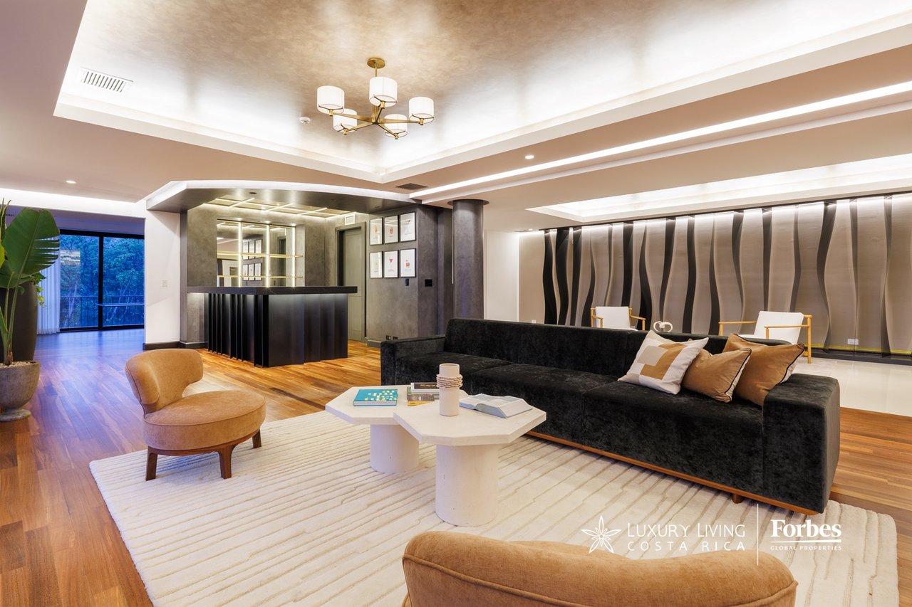 Penthouse living room with a black sectional, sculptural accent wall, and hardwood floors.