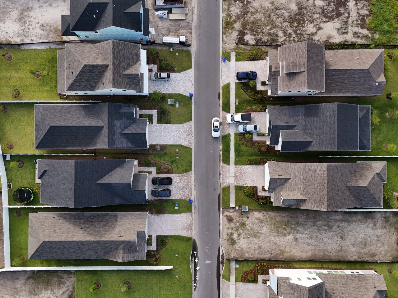 Aerial view of neighboring homes along a residential street, with driveways and lawns.
