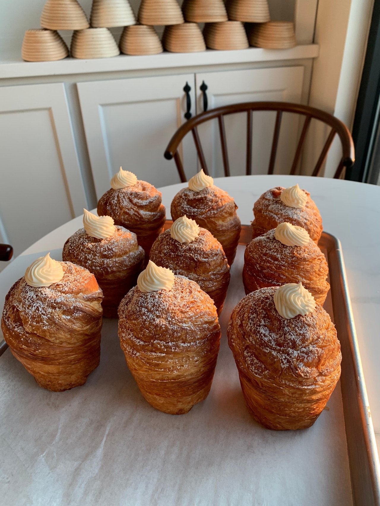 Flaky pumpkin spice cruffin filled with pumpkin spice cream and topped with pumpkin icing and seeds for a seasonal fall treat.