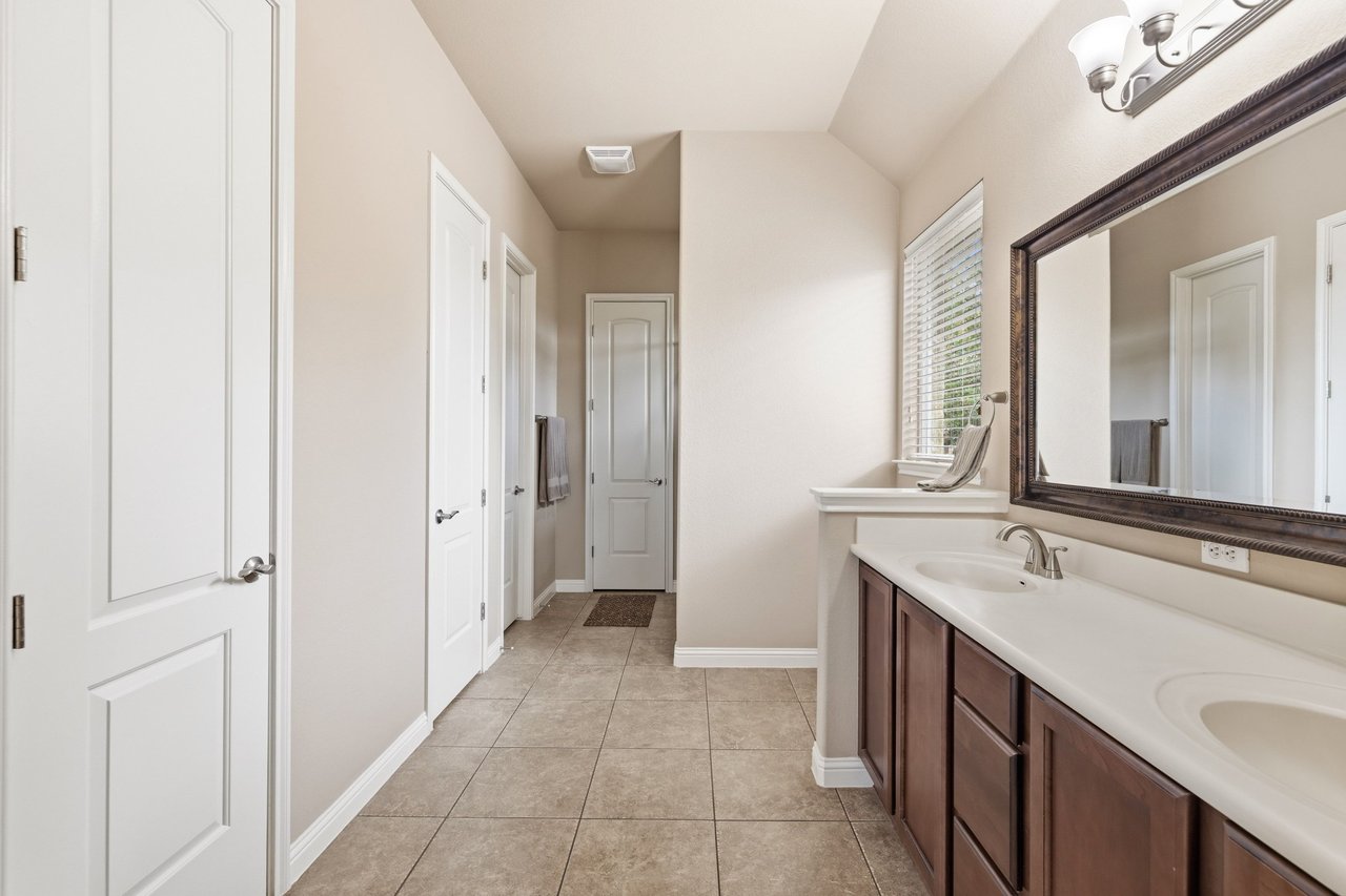 Bathroom with a dark-wood double vanity, two sinks, and a large framed mirror.