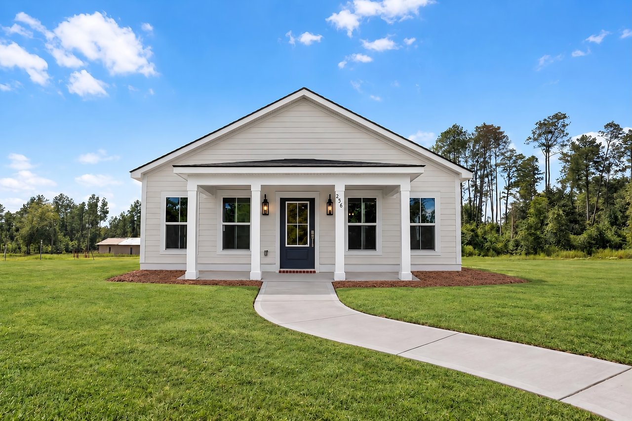 White single-story home with a covered porch, blue door, and curved walkway.