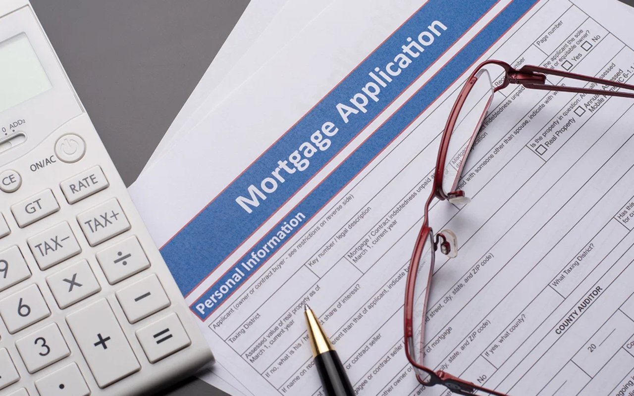 Mortgage application form with a calculator, red-framed glasses, and a pen.