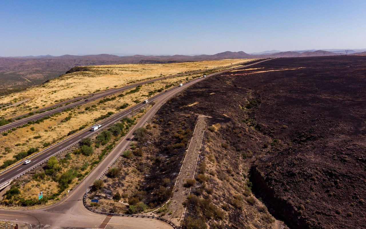 Two highways cross a broad desert landscape, with low mountains on the horizon.