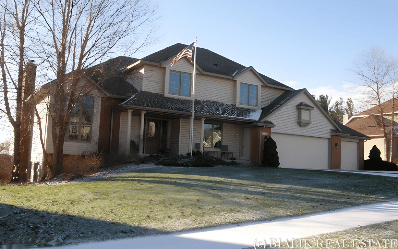Two-story home with an attached double garage and an American flag in the front yard.