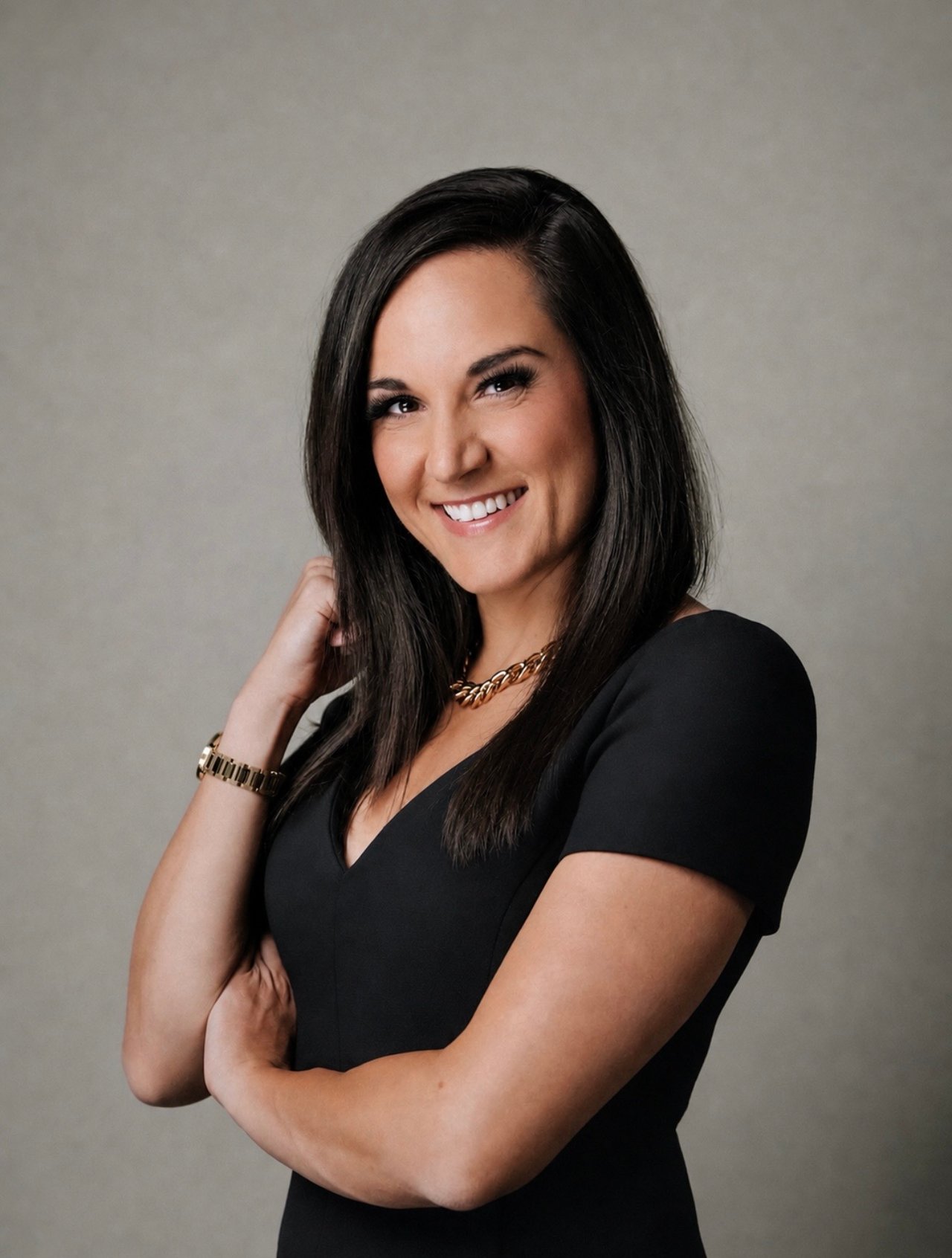Stephanie smiling in a black dress with gold jewelry.