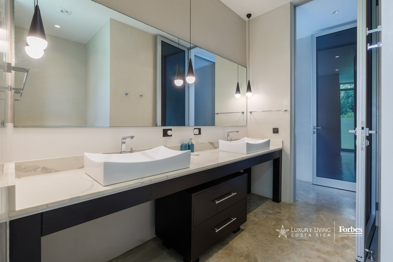 Modern bathroom with a long double-sink vanity, large mirror, and pendant lights.