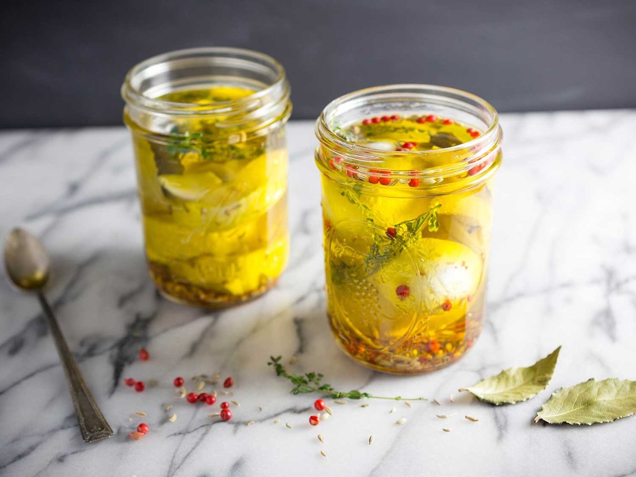 Herbed goat cheese appetizer layered with dill, basil, and olive oil in a small jar.