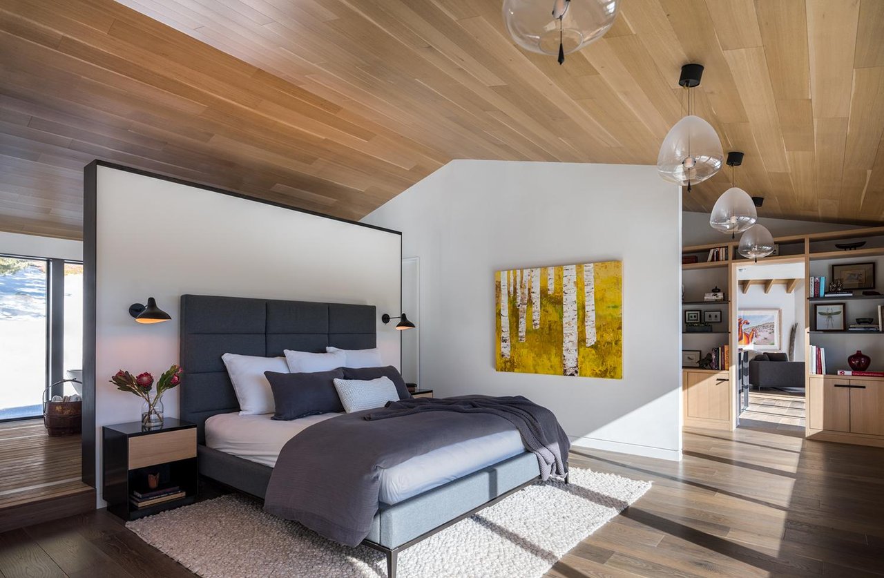Modern Boulder primary bedroom with birch tree artwork, glass globe lights, and built-in storage behind grey upholstered bed