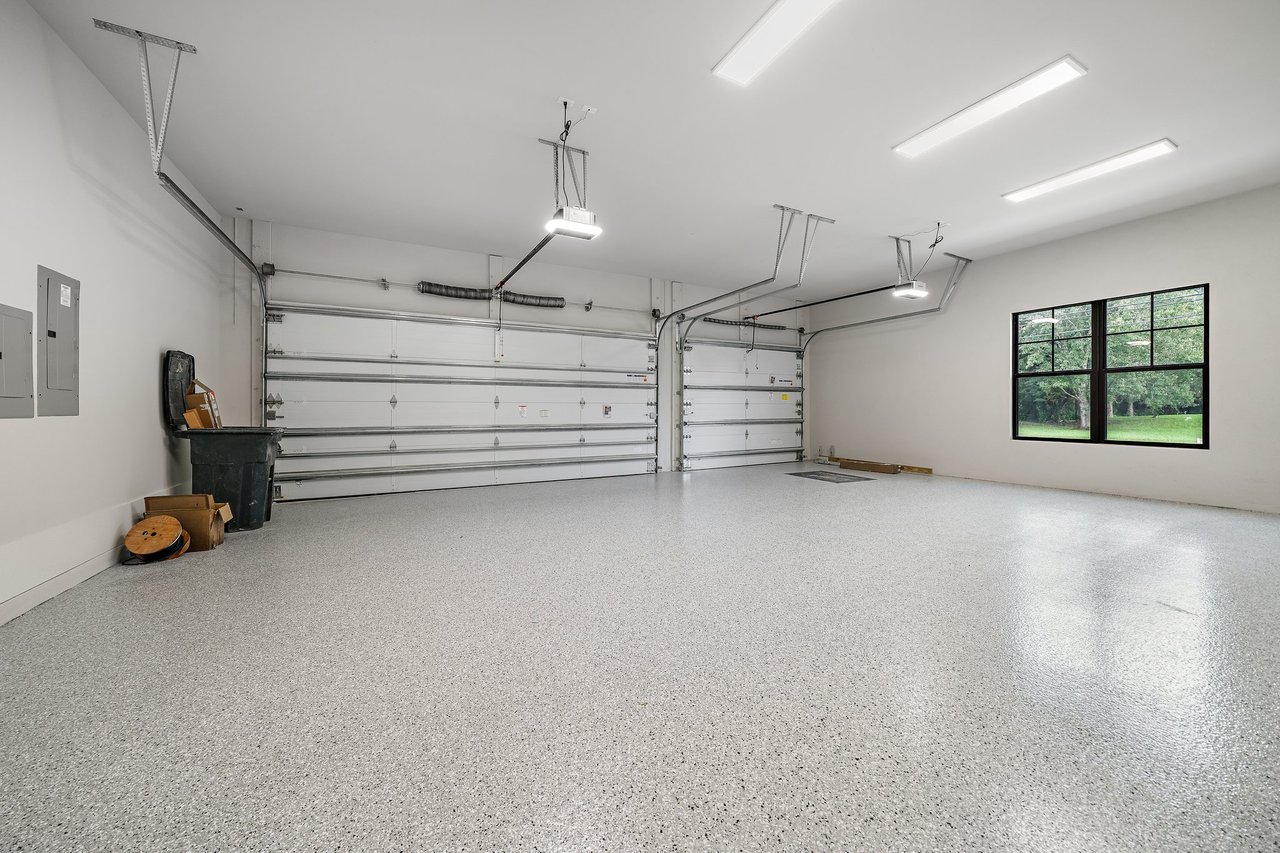 Two-bay garage with speckled epoxy flooring and a large window overlooking greenery.