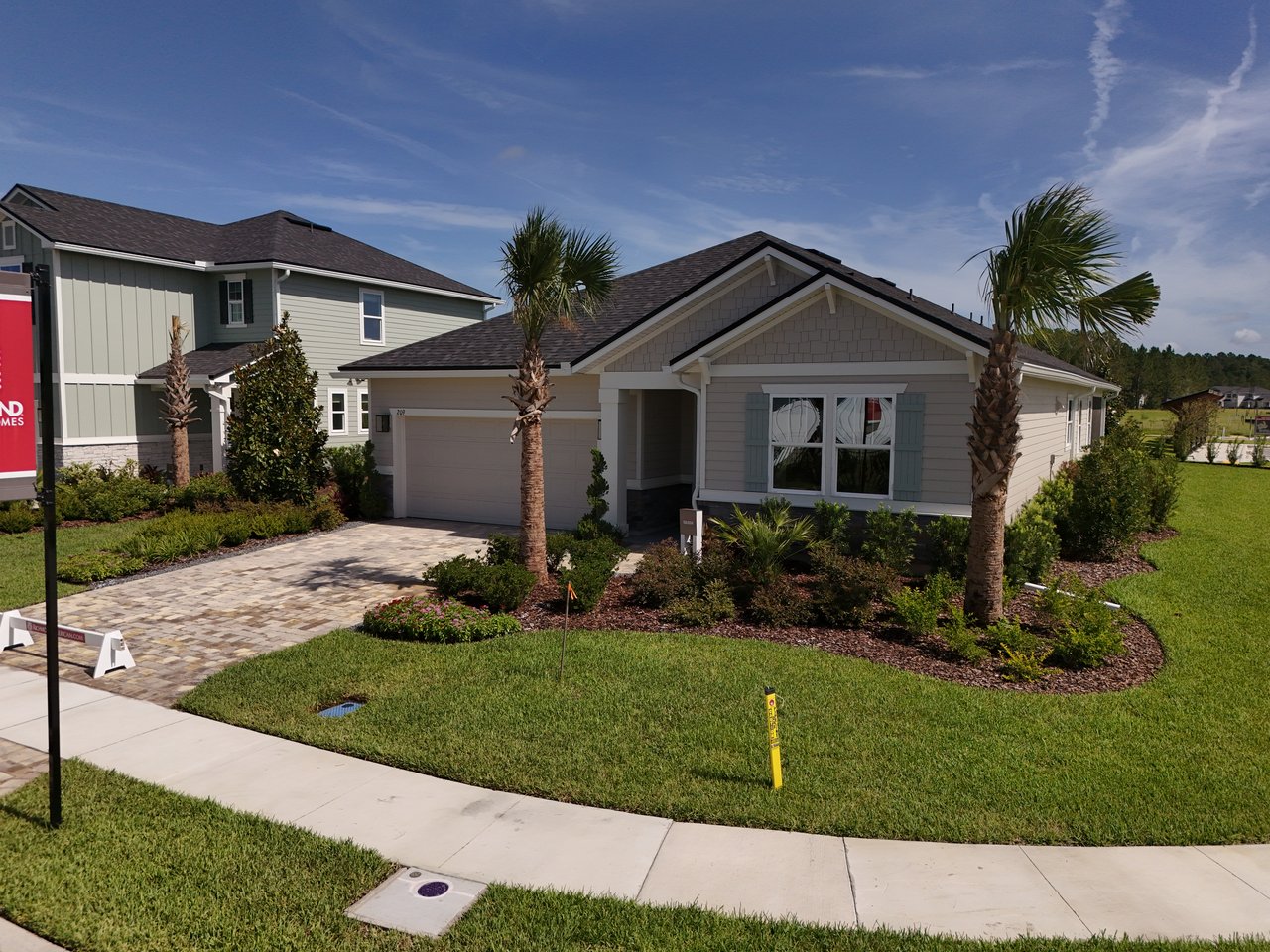 Single-story home with a dark gabled roof, paved driveway, and palm trees in the front garden.
