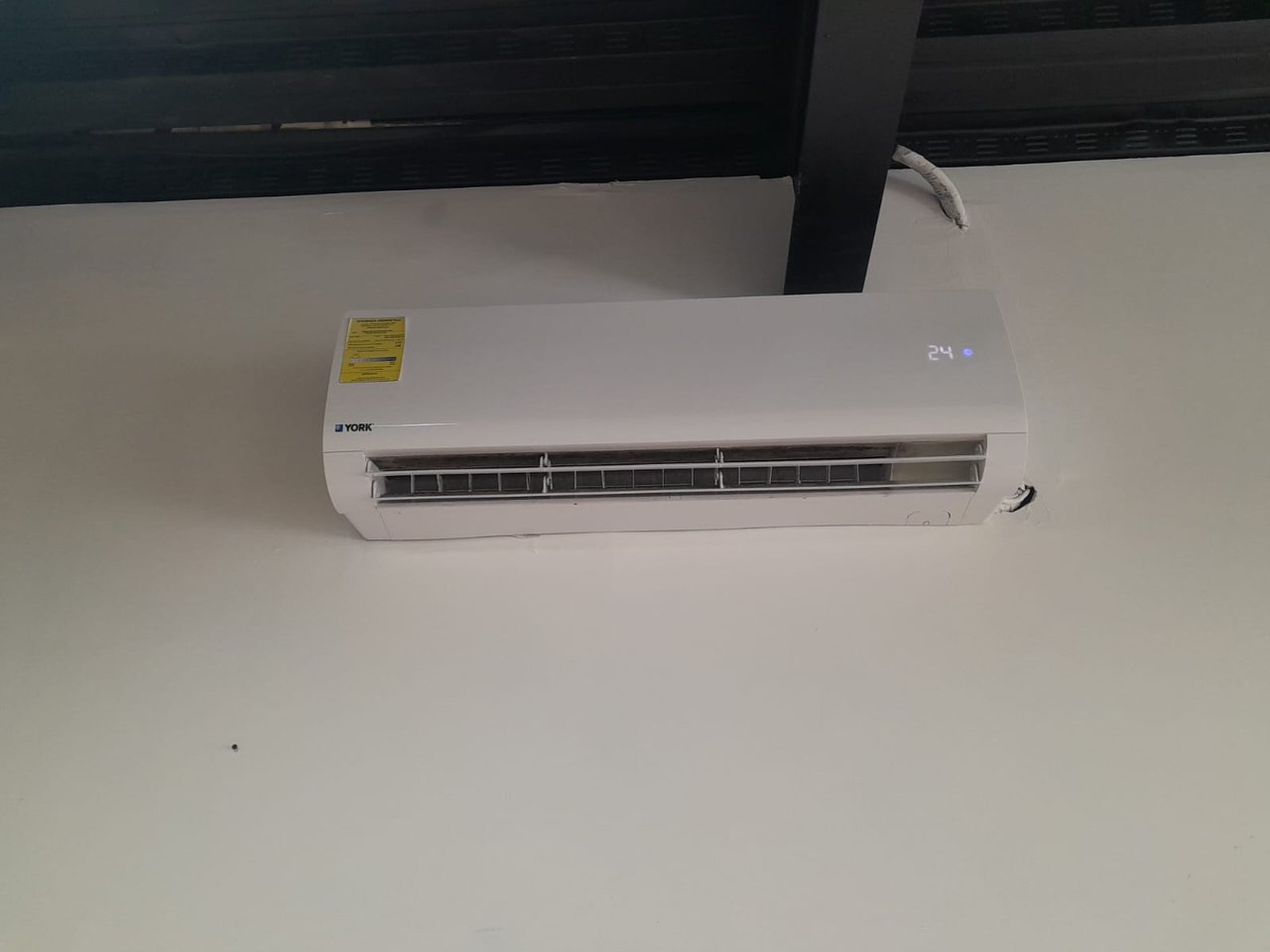 Wall-mounted York air conditioner with open vent and 24° display.
