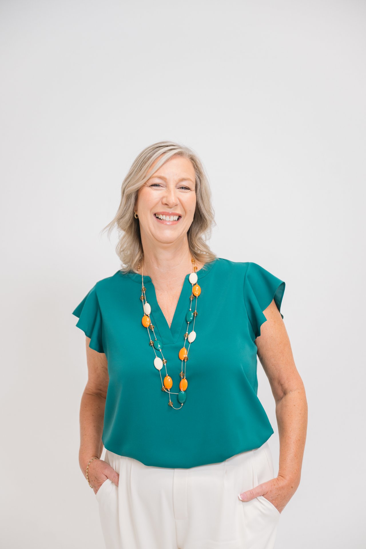 Simone Robinson smiling in a teal blouse and multicolored necklace