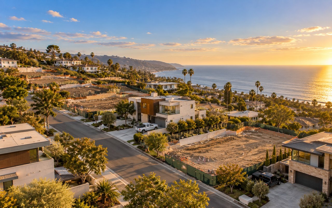 Cleared residential lot in Pacific Palisades with survey stakes and a new home under construction in the background, September 2026