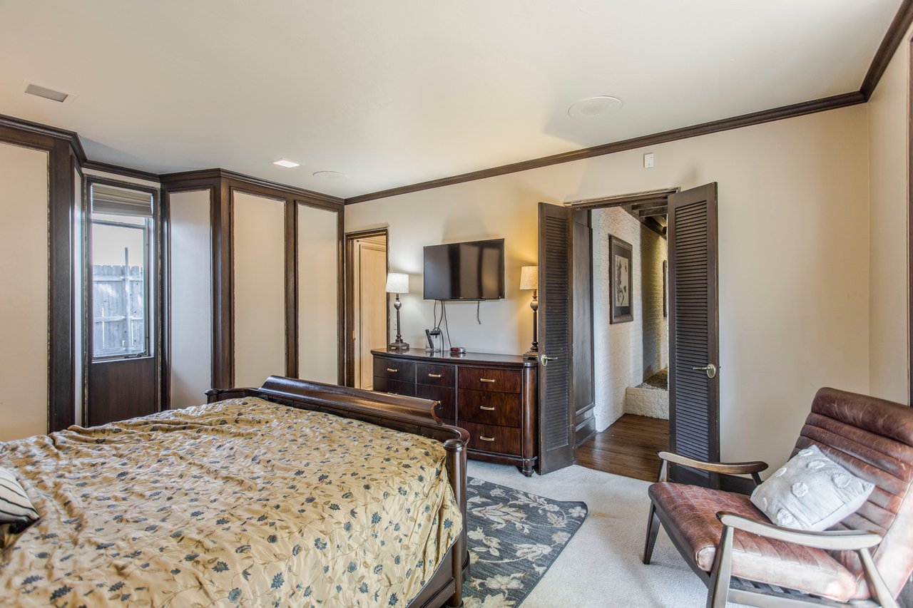 Bedroom with patterned bedding, dark wood trim, and a television above a dresser.