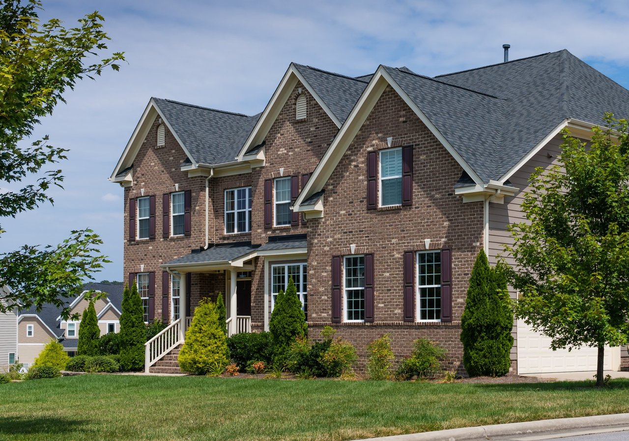 Two-story brick house with steep gables, a front porch, and landscaped lawn.