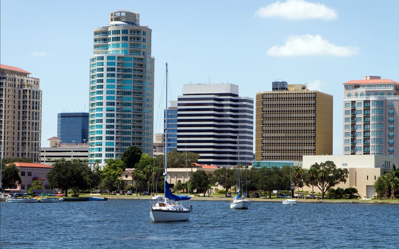 Waterfront skyline with sailboats on the bay and high-rise buildings along the shore.