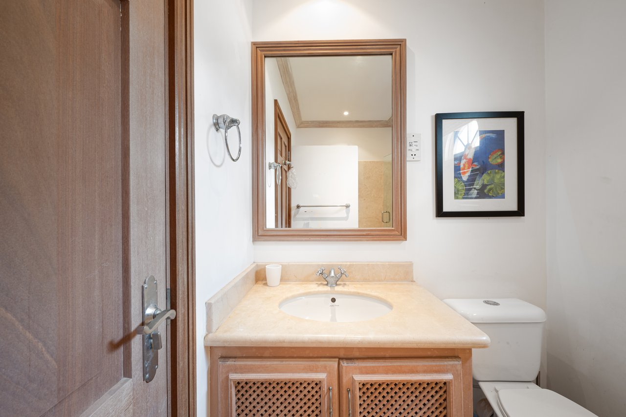 Bathroom with a wood vanity, cream stone countertop, oval sink, and framed mirror.