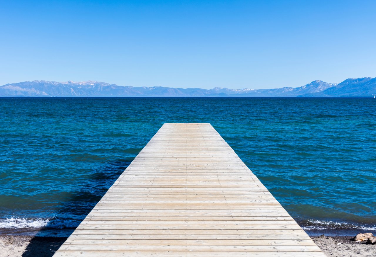 Aerial view of luxury lakefront homes in Lake Tahoe under clear blue skies, showcasing current real estate trends.