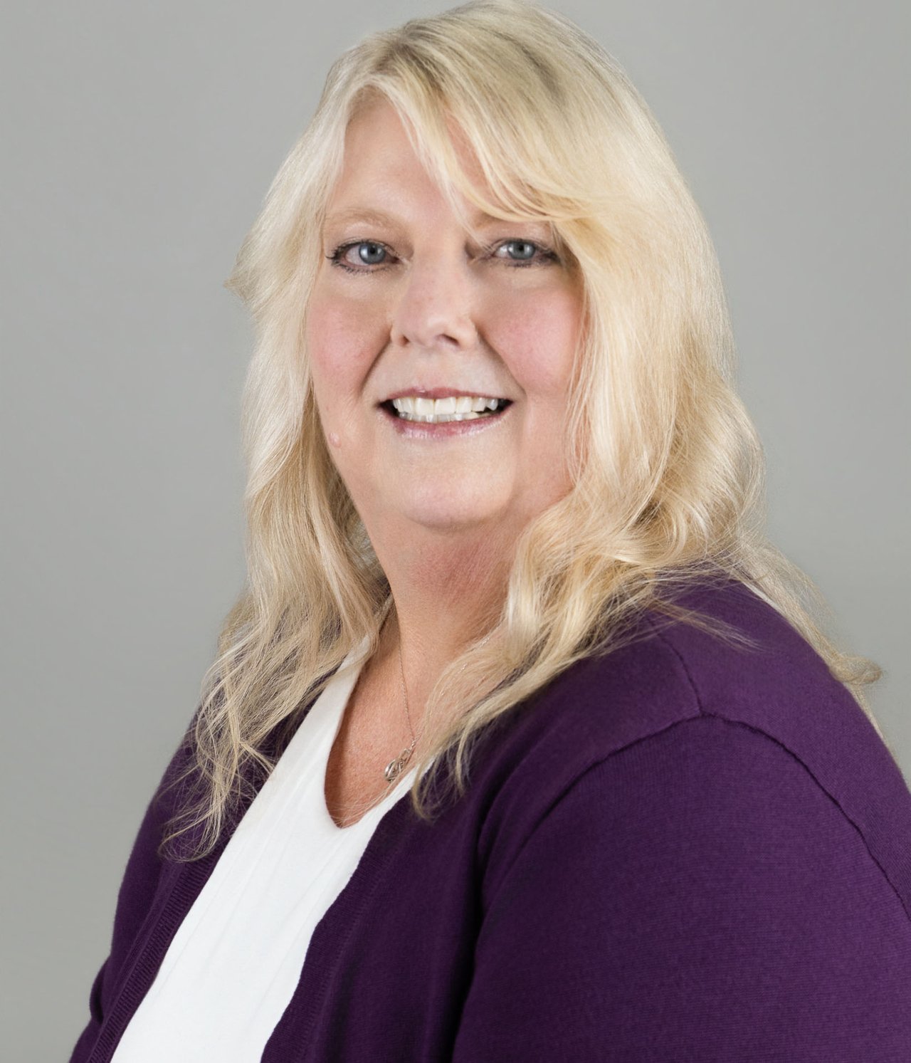 Doretta Reynolds, smiling in a purple cardigan and white top.