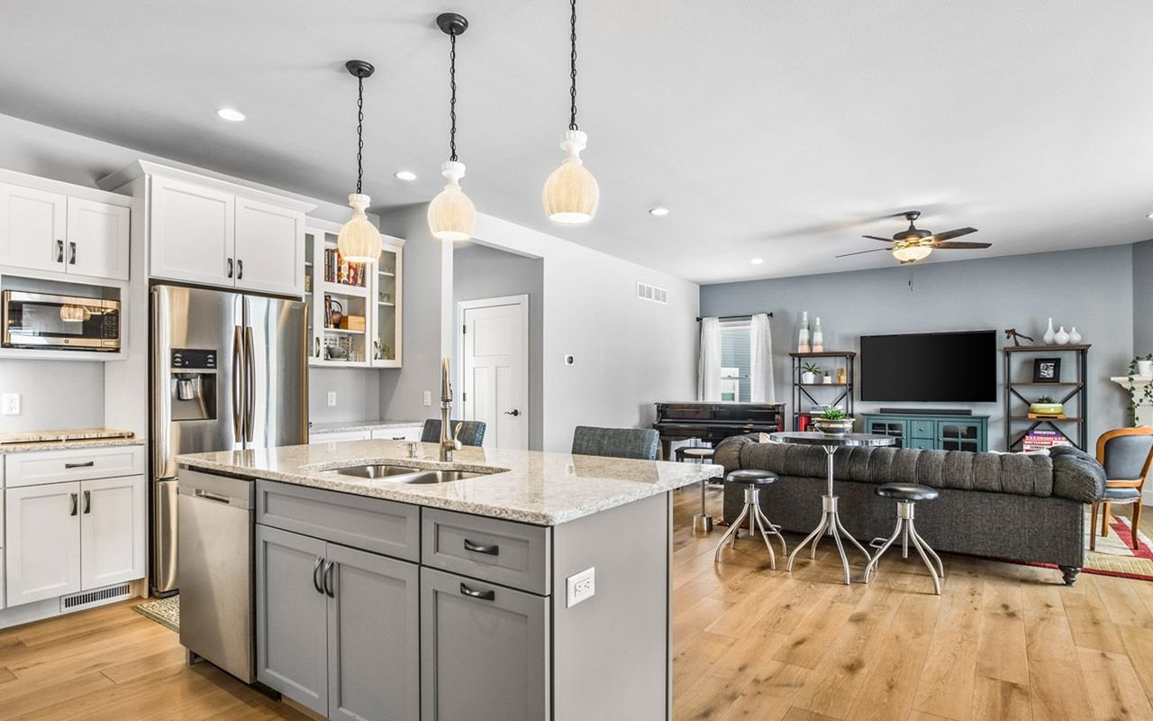 Open-plan kitchen and living room with a stone island, stainless appliances, and hardwood floors.