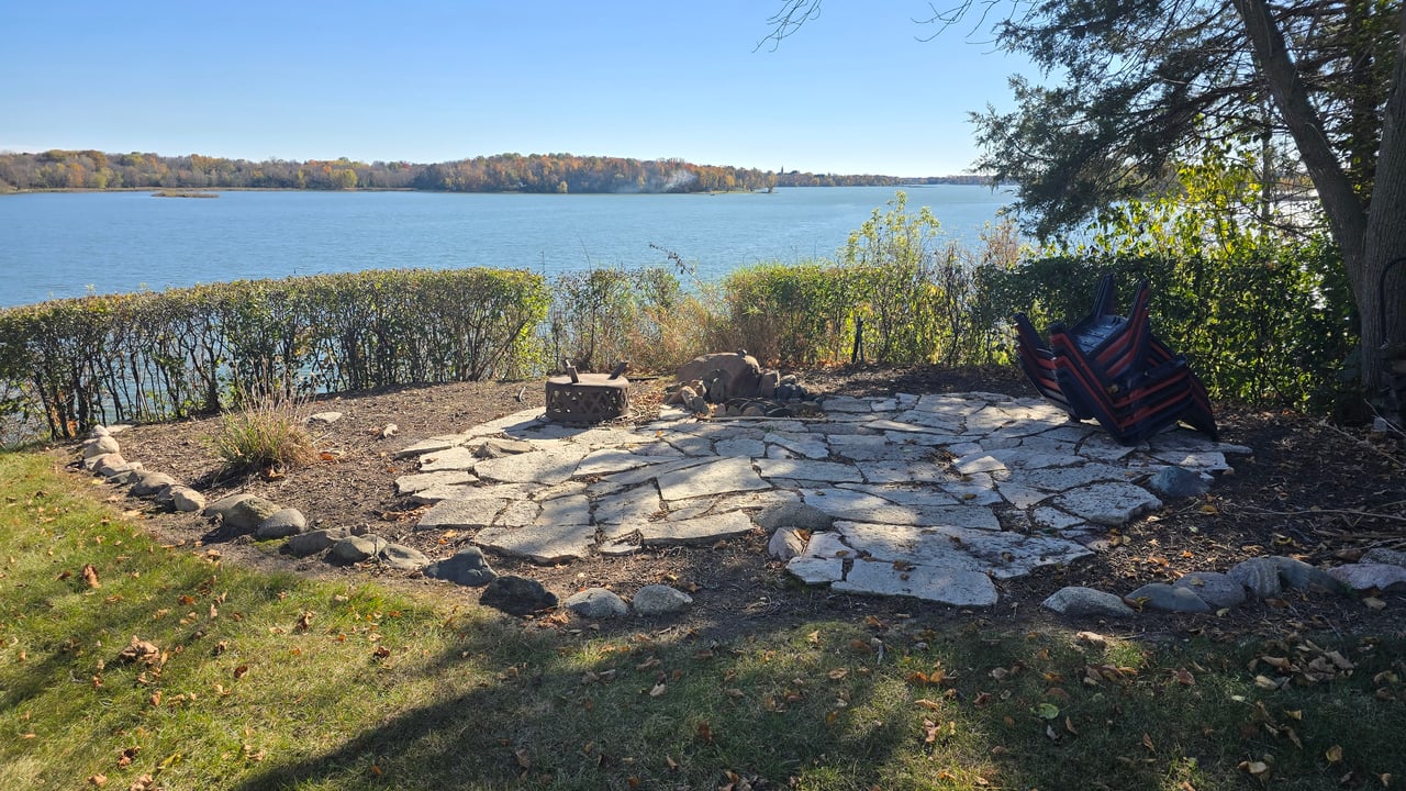 Lakeside yard with a flagstone patio and fire pit overlooking the water.