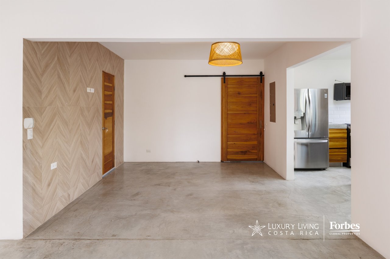 Unfurnished room with a concrete floor, herringbone wood wall, sliding barn door, and kitchen opening.
