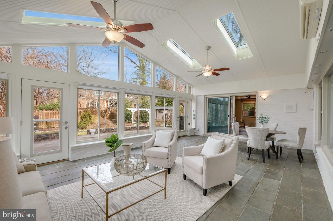 Sunroom with skylights, vaulted ceiling, large garden-facing windows, and white seating.