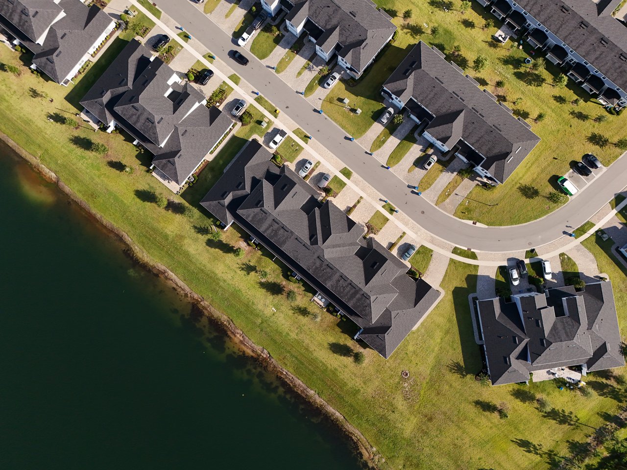 Aerial view of homes along a pond, with curving streets and lawns.