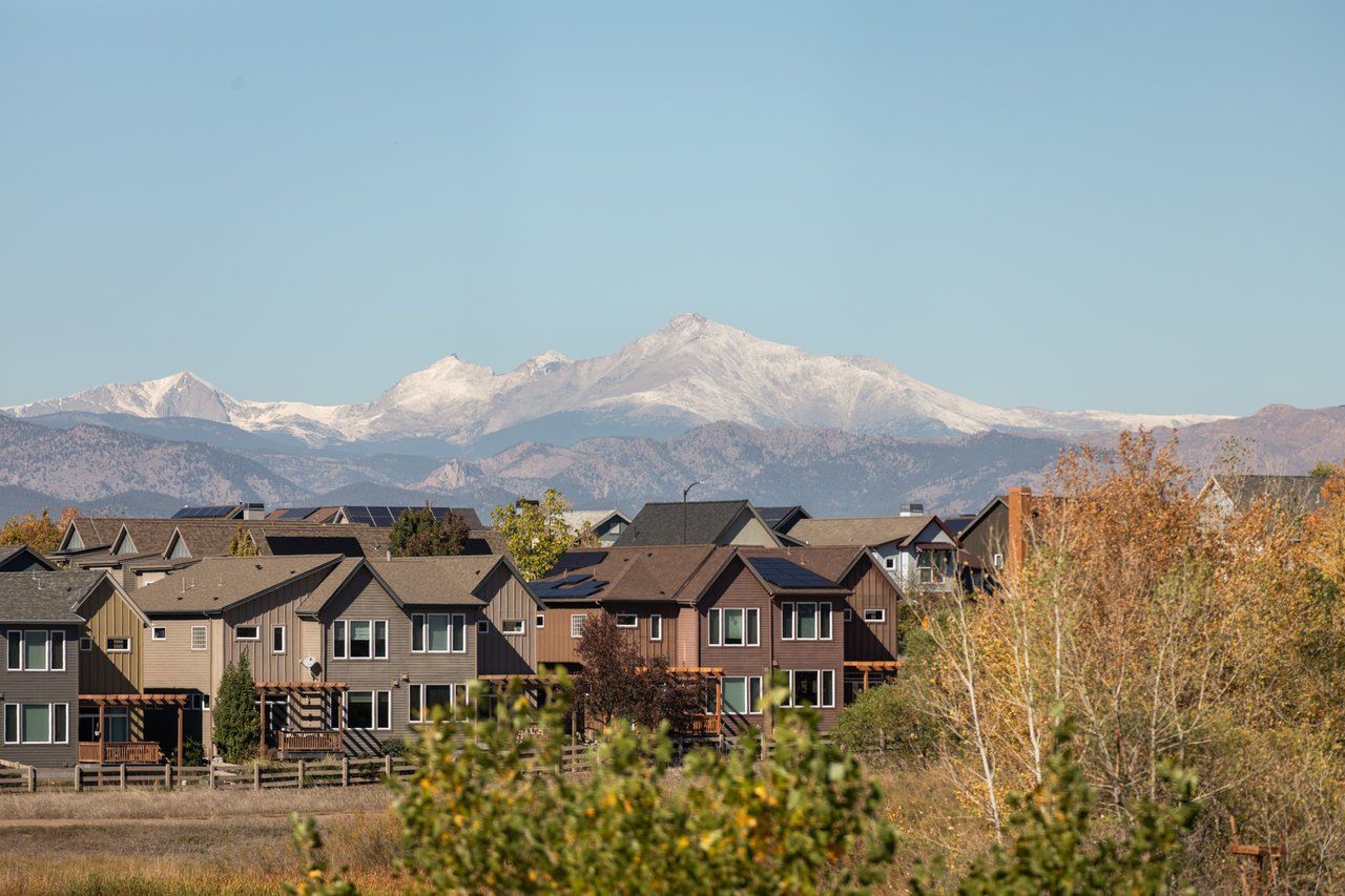 Snow-capped mountain peaks above neighborhood rooftops and fall foliage