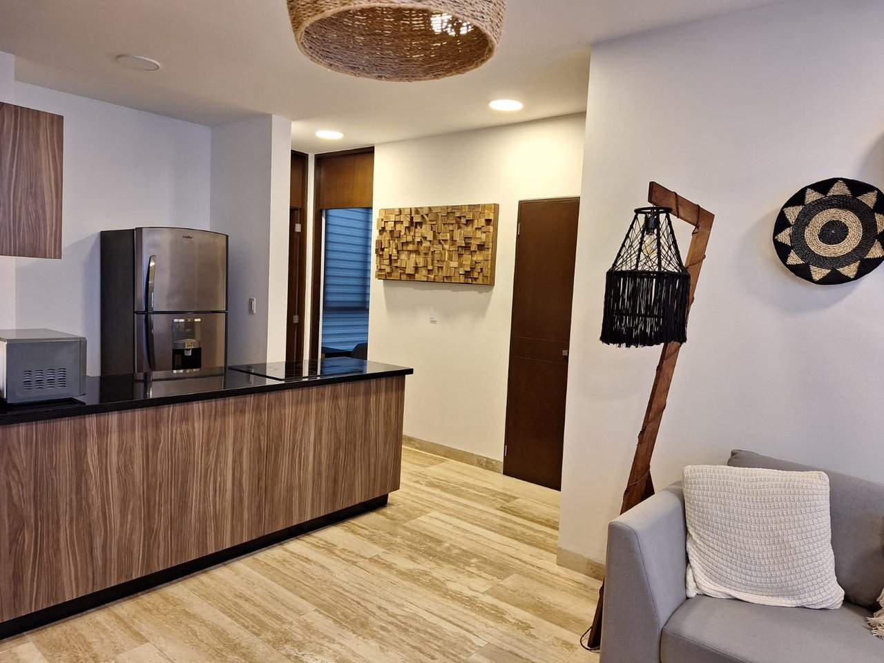Condo kitchen with a wood-front island, stainless steel refrigerator, and gray sofa.