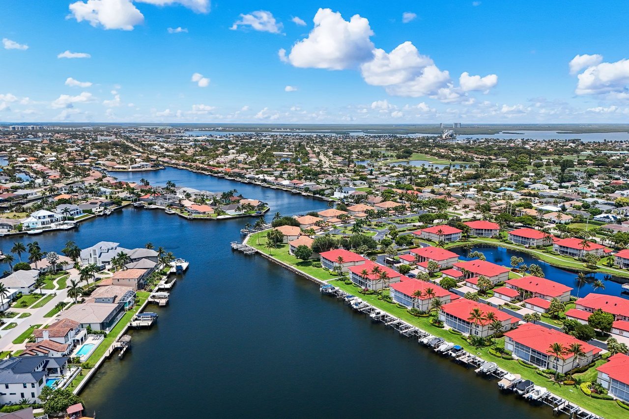 Aerial view of waterfront homes and docks along a wide canal.