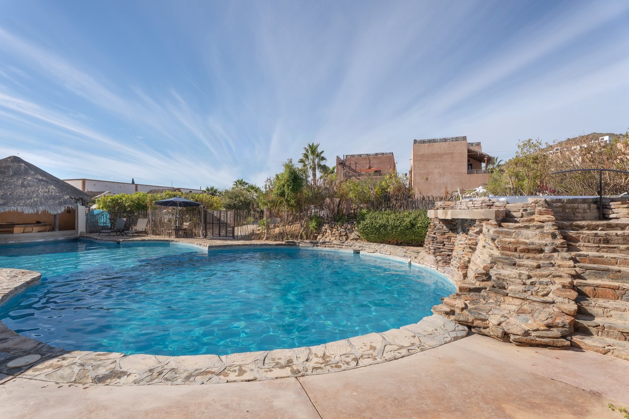 Main pool at Villas de Cerritos with mature landscaping, palm trees, and community amenities in Cerritos, Baja California Sur.