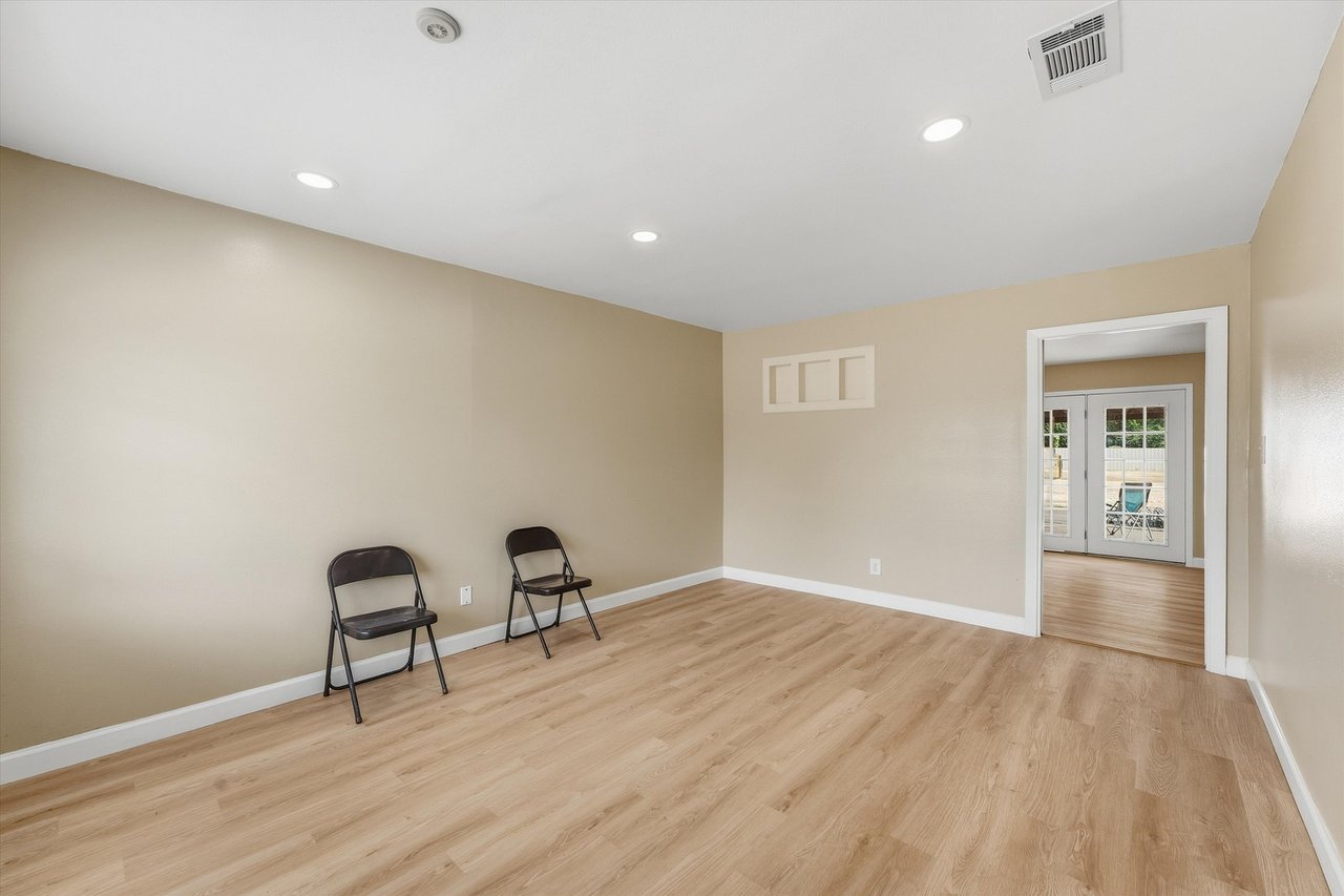 Spare room with light wood-look flooring, beige walls, and two folding chairs.