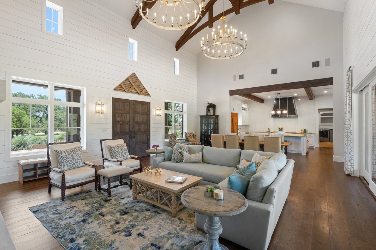 Great room at 335 Winning Colors with vaulted ceilings, wood beams, and twin chandeliers, opening to a rustic wood entry door.