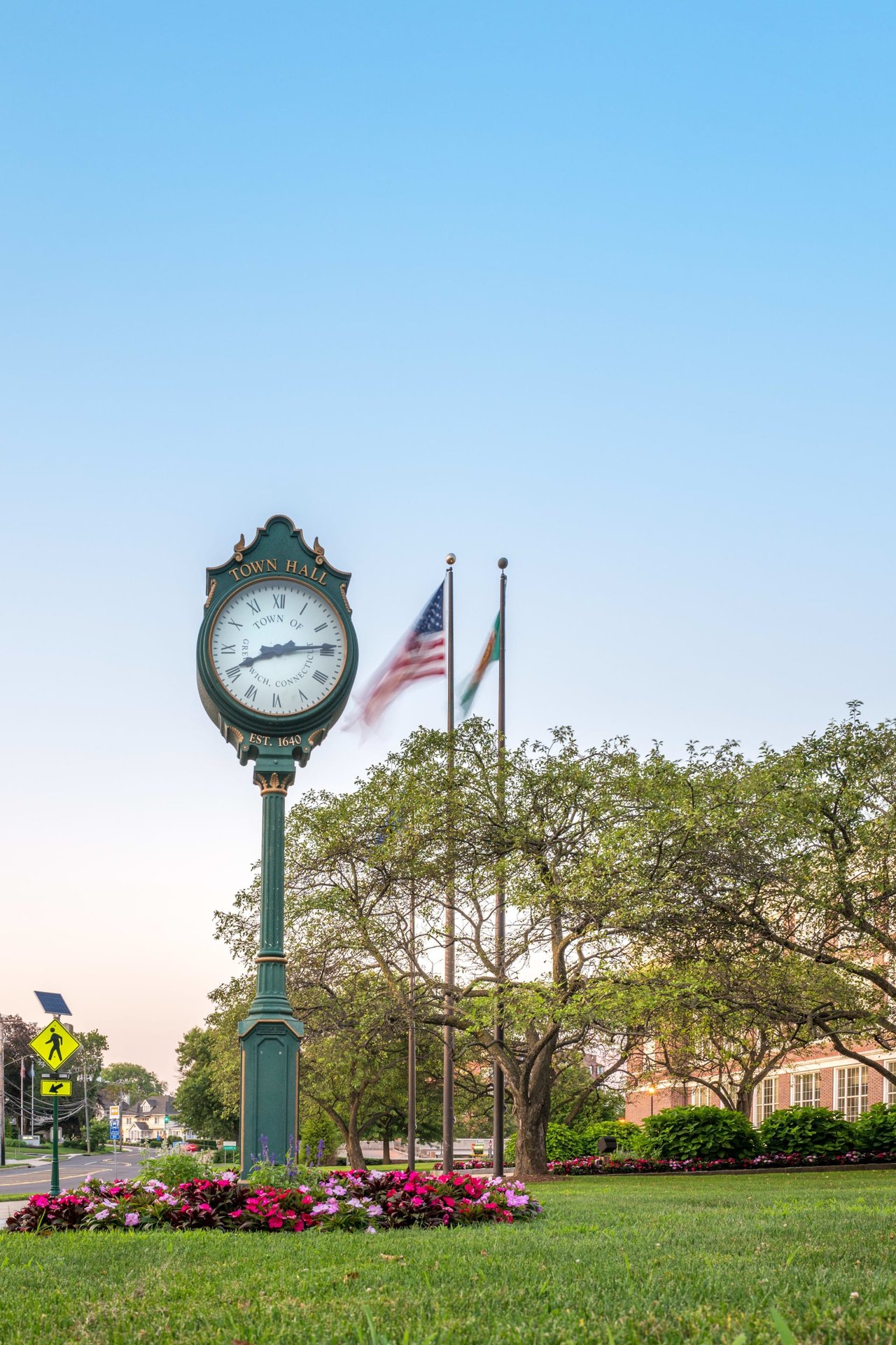 A town hall tower clock in a green space.