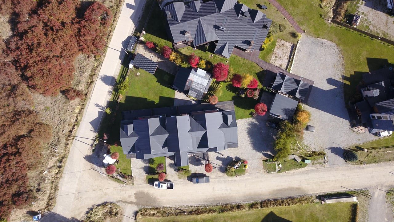 Aerial view of dark-roofed buildings surrounded by landscaped grounds and autumn trees.