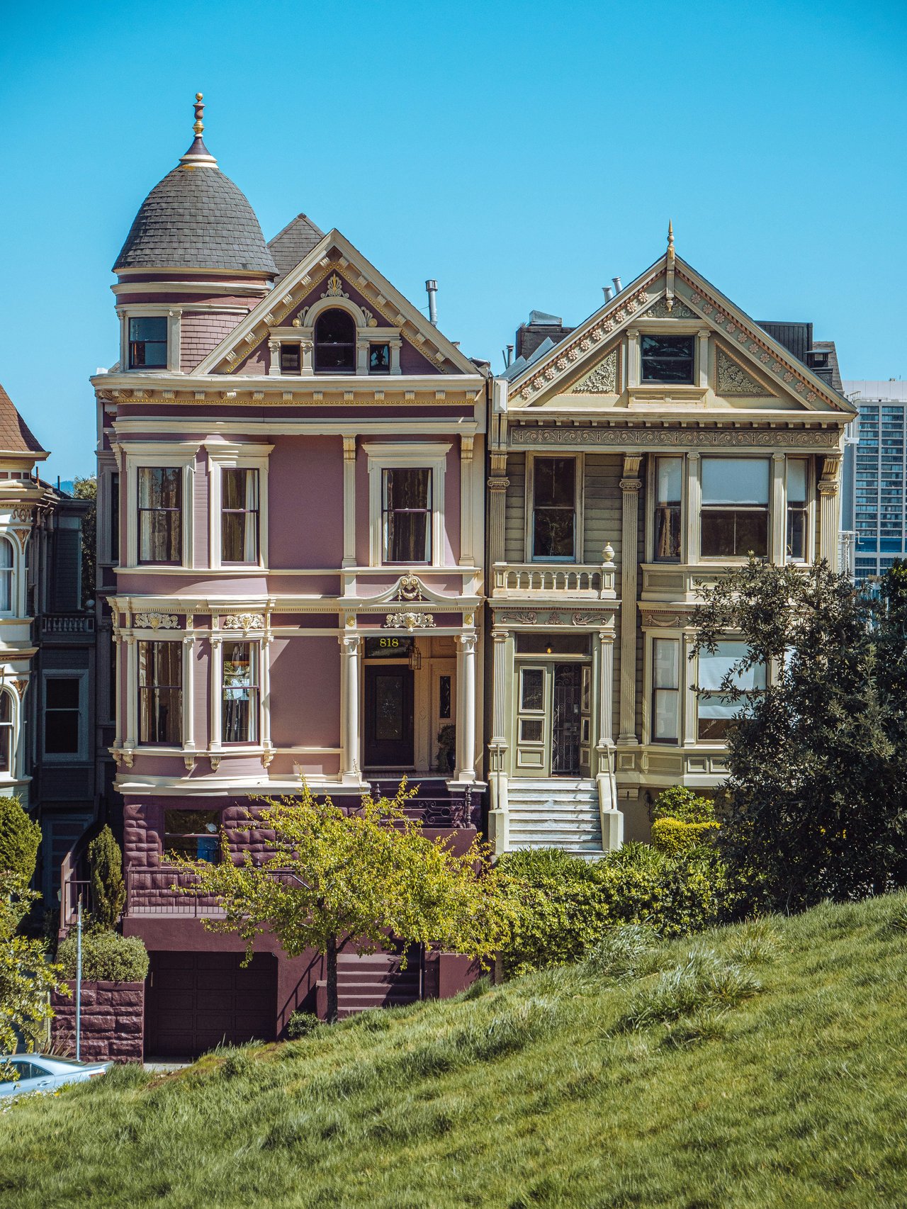 Ornate Victorian mansion with a turret set on a grassy hillside lawn