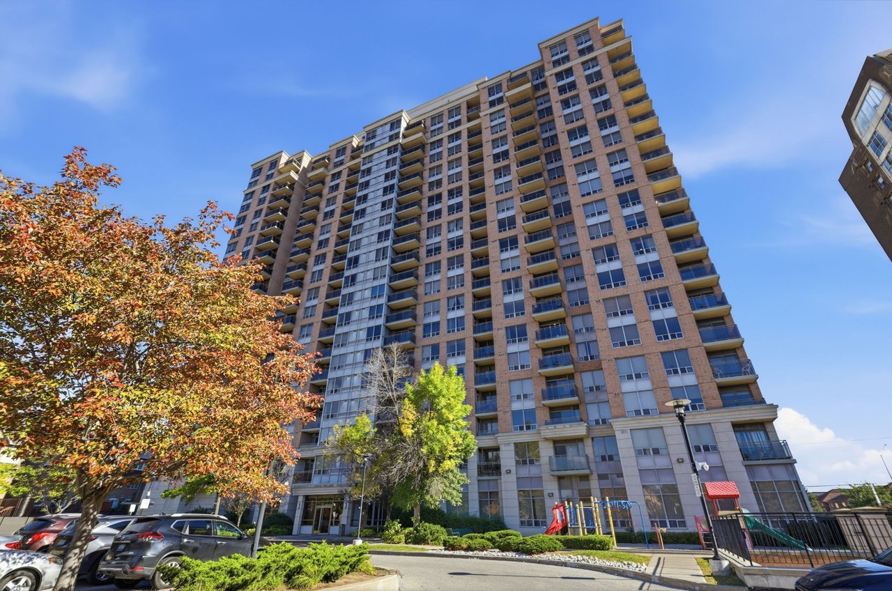 Strathaven condominium tower with rows of balconies, autumn trees, and a playground at its base.