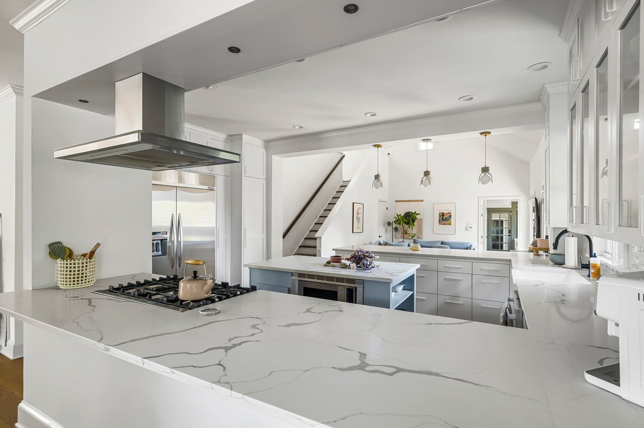 Two-story family room and kitchen island with quartz counters at 1500 Northwood Rd, Pemberton Heights, Austin. Renovation by McWalters Collaborative.