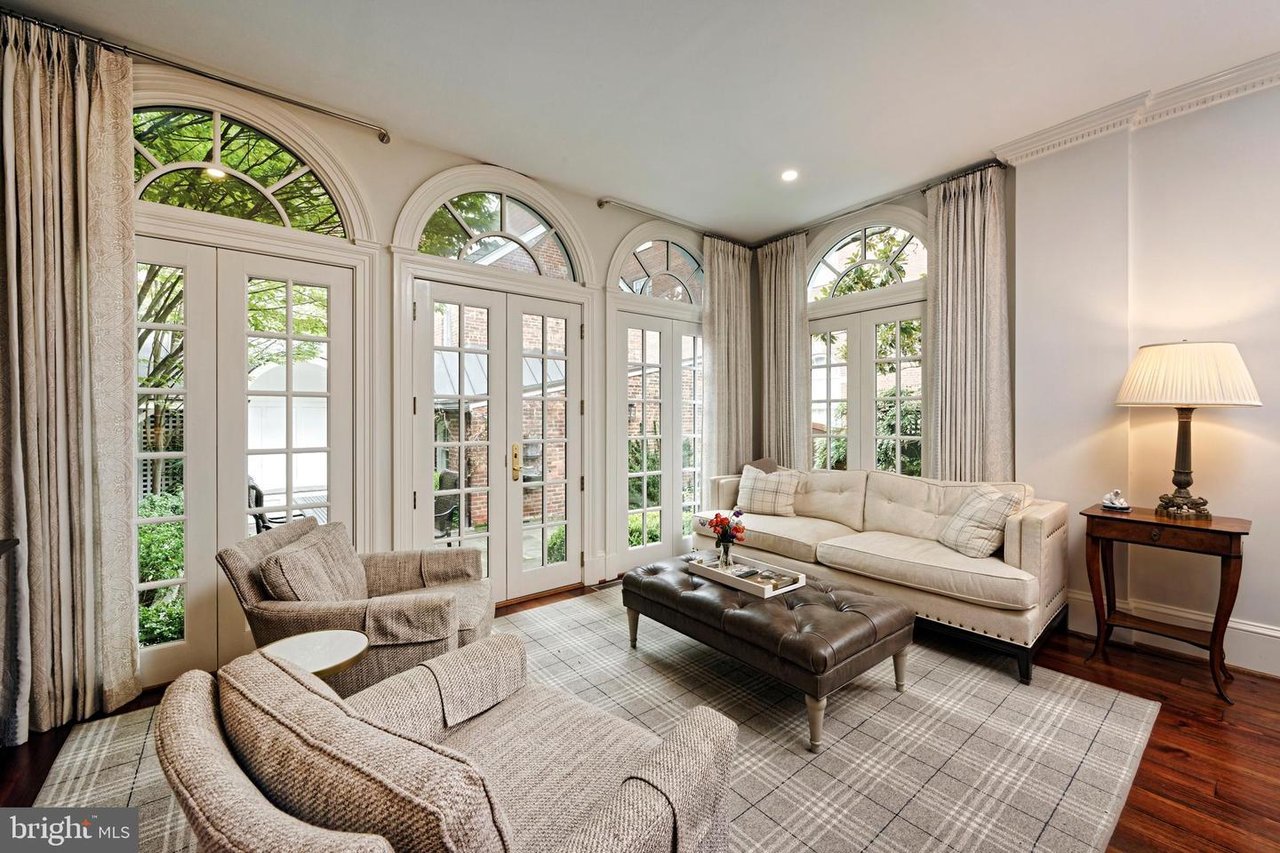 Living room with arched windows, French doors, cream seating, and a plaid rug.