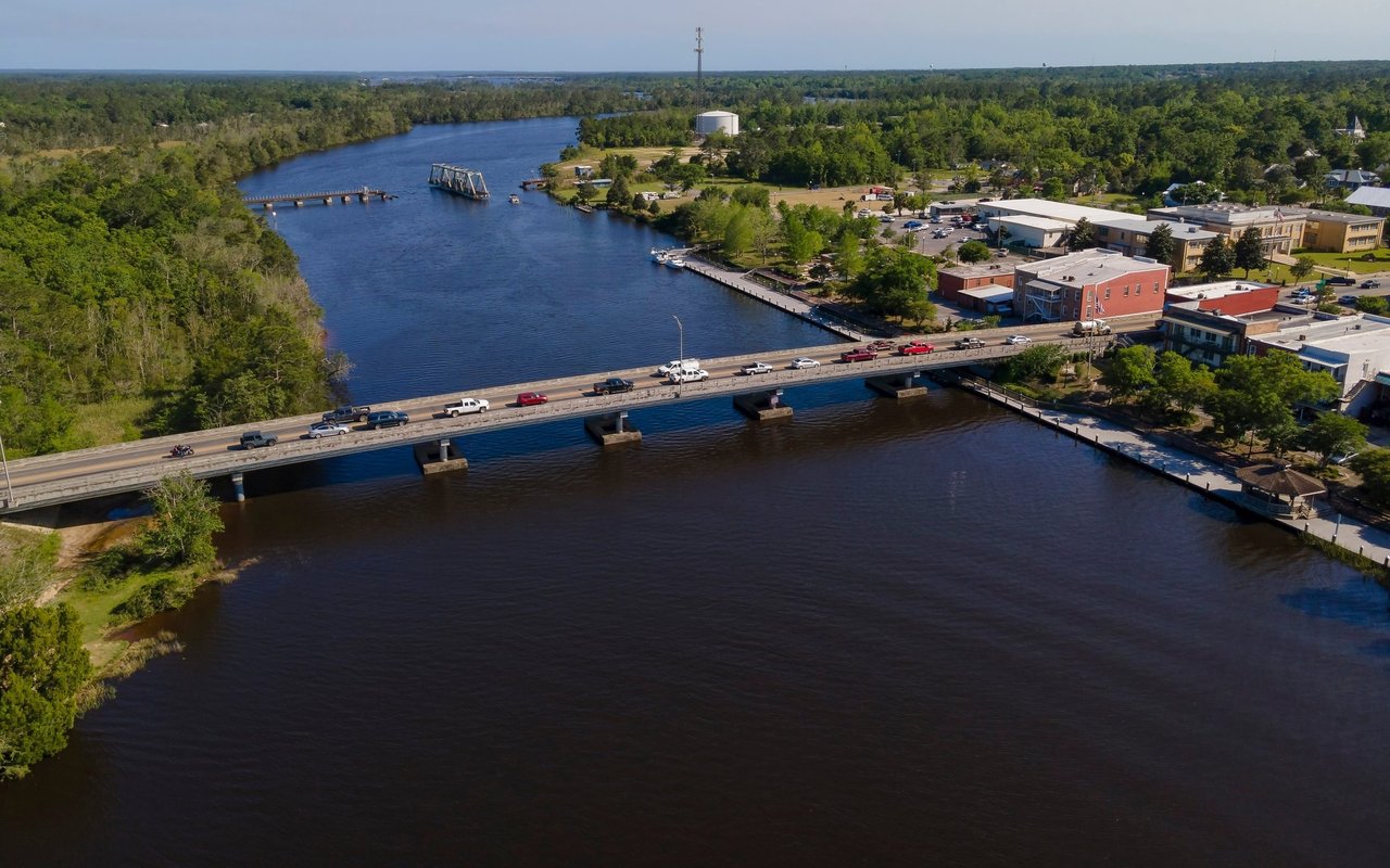 Aerial view of Milton’s riverfront, with a bridge crossing the river beside downtown buildings.