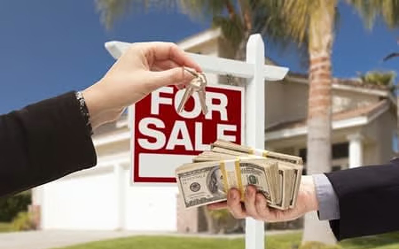 Home for sale with keys being hung on the sign and cash offered in the foreground.